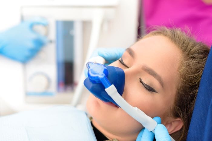 Patient in dental chair wears a blue nitrous oxide mask