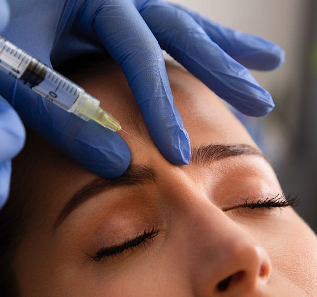 Close-up of a person receiving a cosmetic injection in the forehead