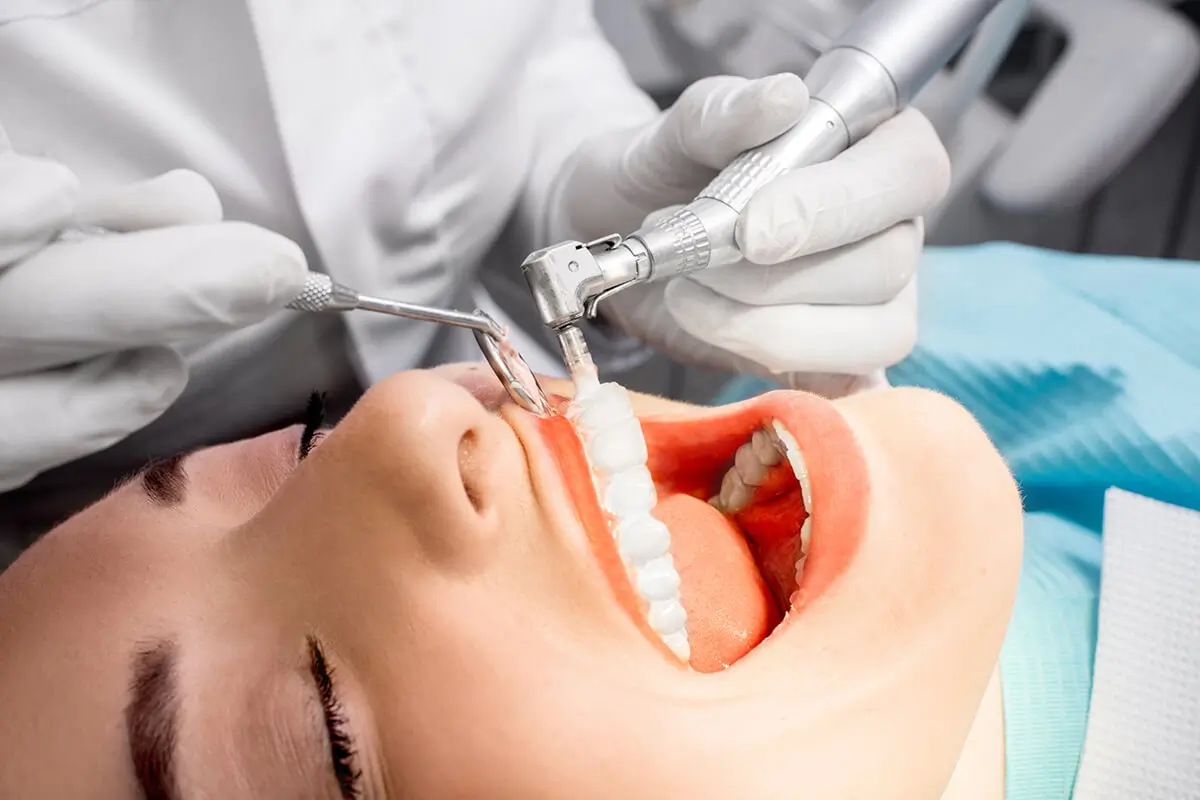Close-up of a patient in a dental chair with open mouth, showing teeth and gums